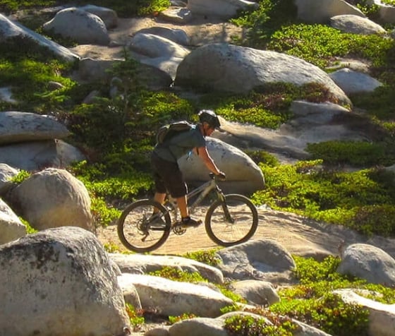 A wide shot of a man riding a bike in the mountains