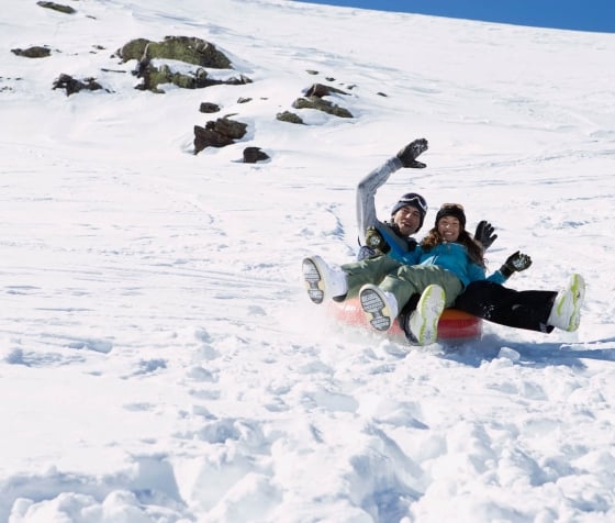A couple on a snow tube sled in the mountains