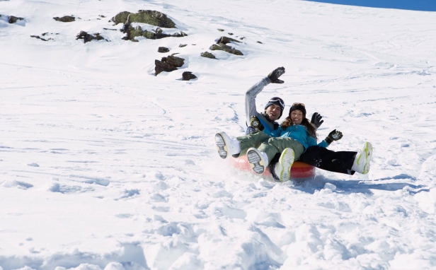 A couple on a snow tube sled in the mountains
