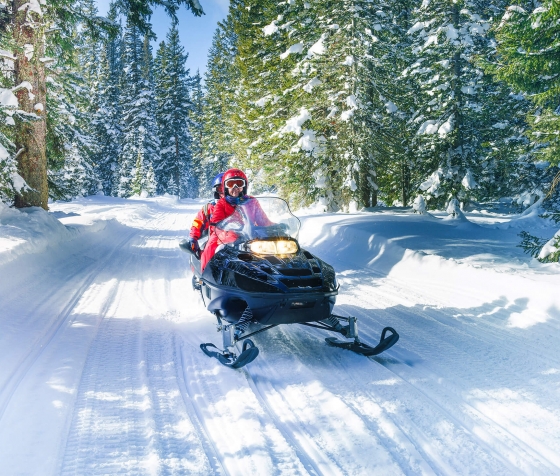 A couple riding a snowmobile in snowy alps during winter