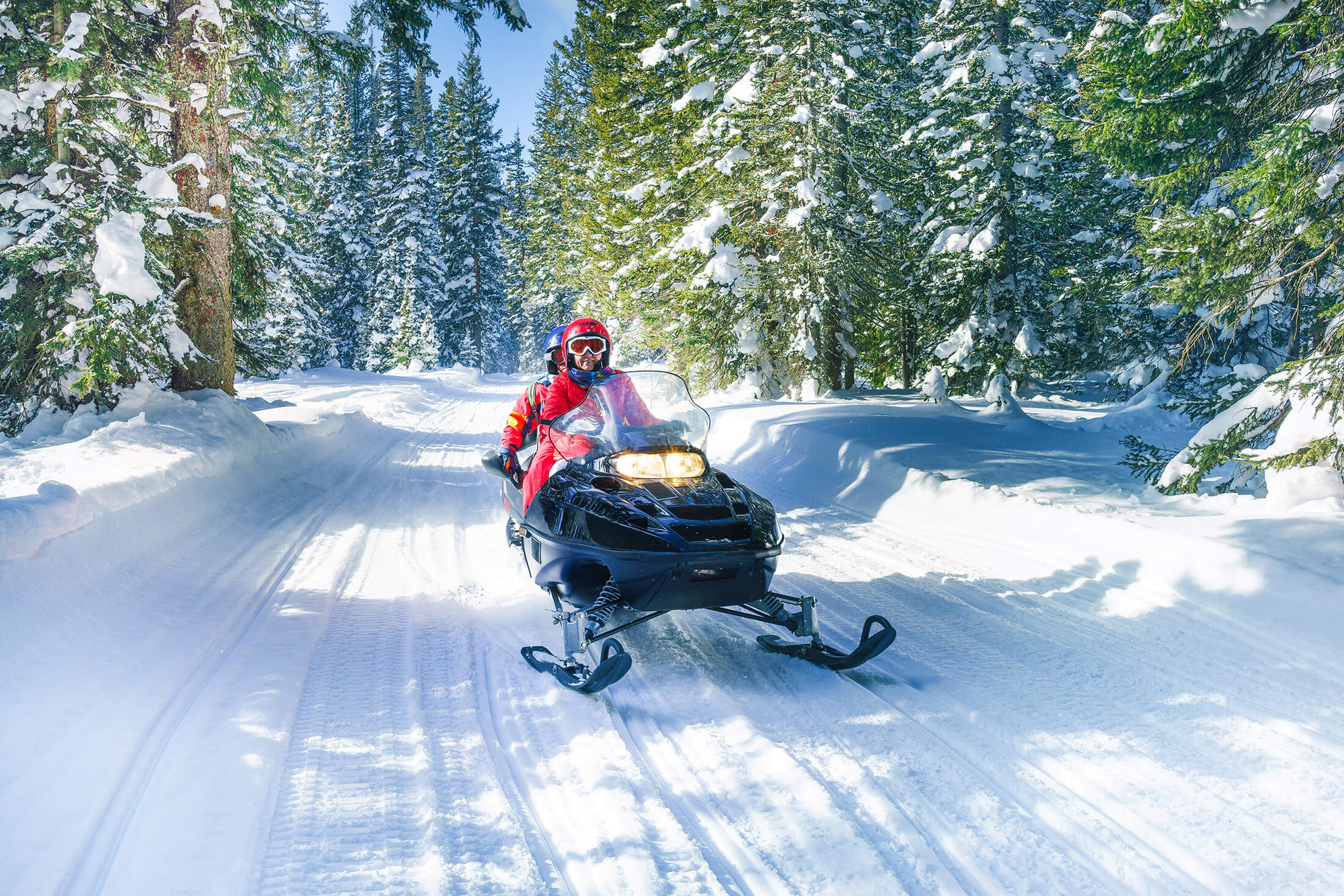 A couple riding a snowmobile in snowy alps during winter