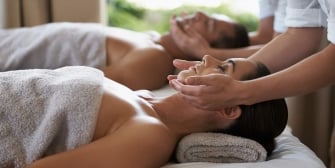A couple receiving facial massage while lying on the massage bed