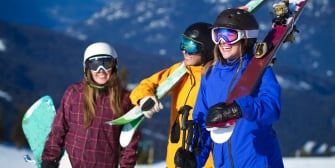 A group of girls with carrying their snowboards during winter