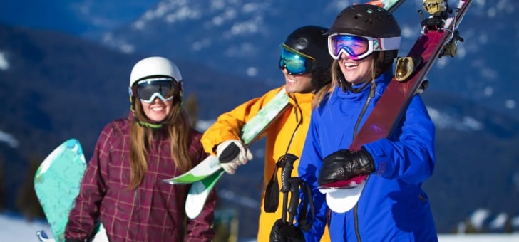 A group of girls with carrying their snowboards during winter