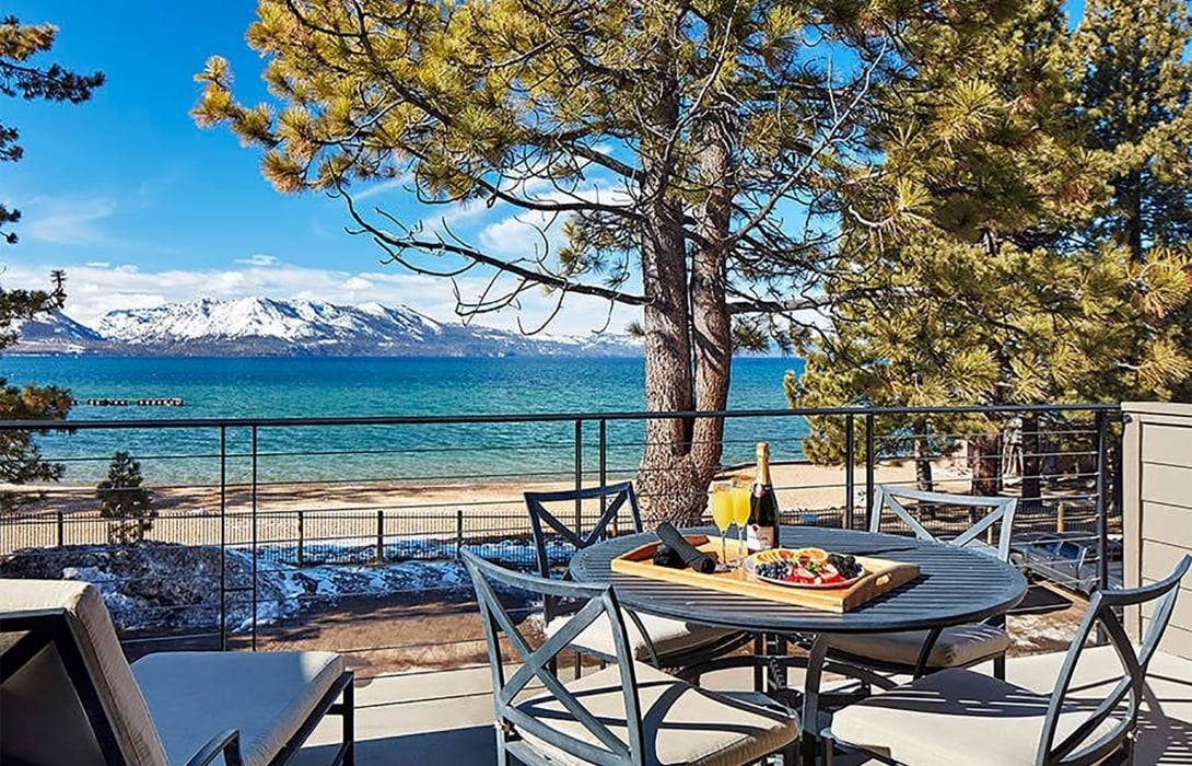 Mimosa glasses, champagne bottle and sliced fruits placed on the outdoor patio table amidst chairs