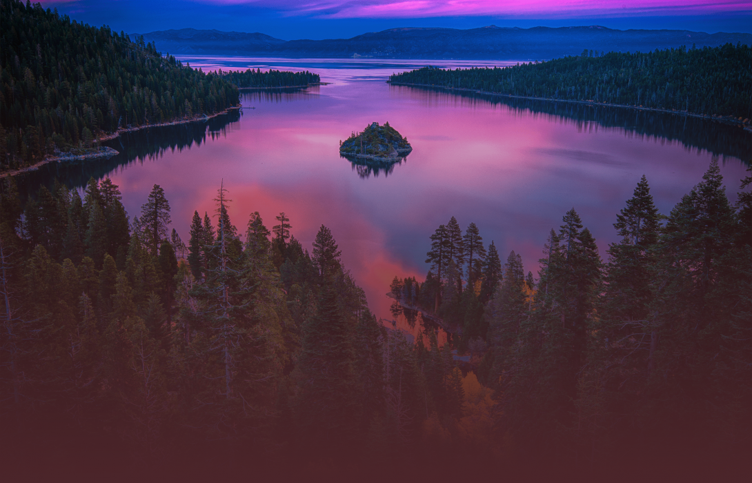 A wide shot of trees surrounding the lake during sunset