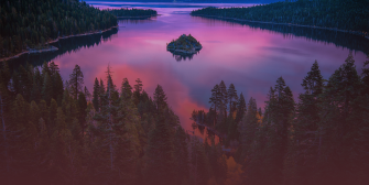 A wide shot of trees surrounding the lake during sunset