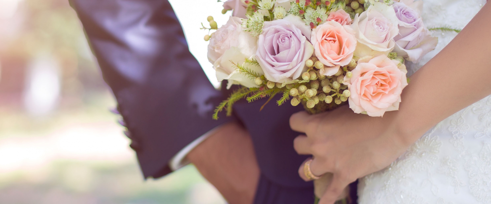 Closeup of the bride's hand holding the flower bouquet next to the groom