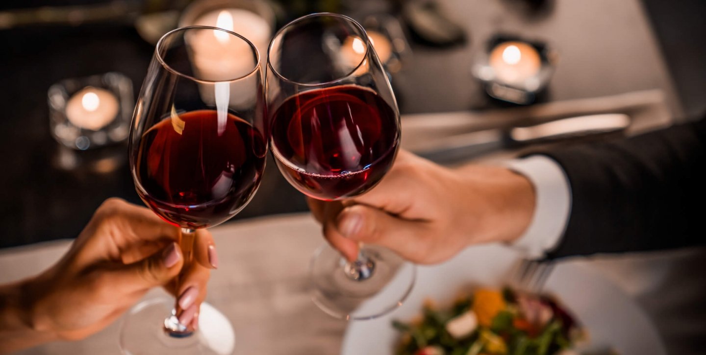 Two hands clinking wine glass into cheers
