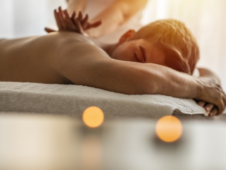 A man lying on his front and receiving a sports massage from the therapist