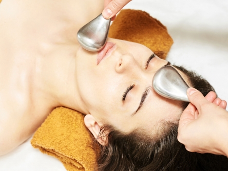 Young woman receiving an ice facial stick massage from the hands of an aesthetician
