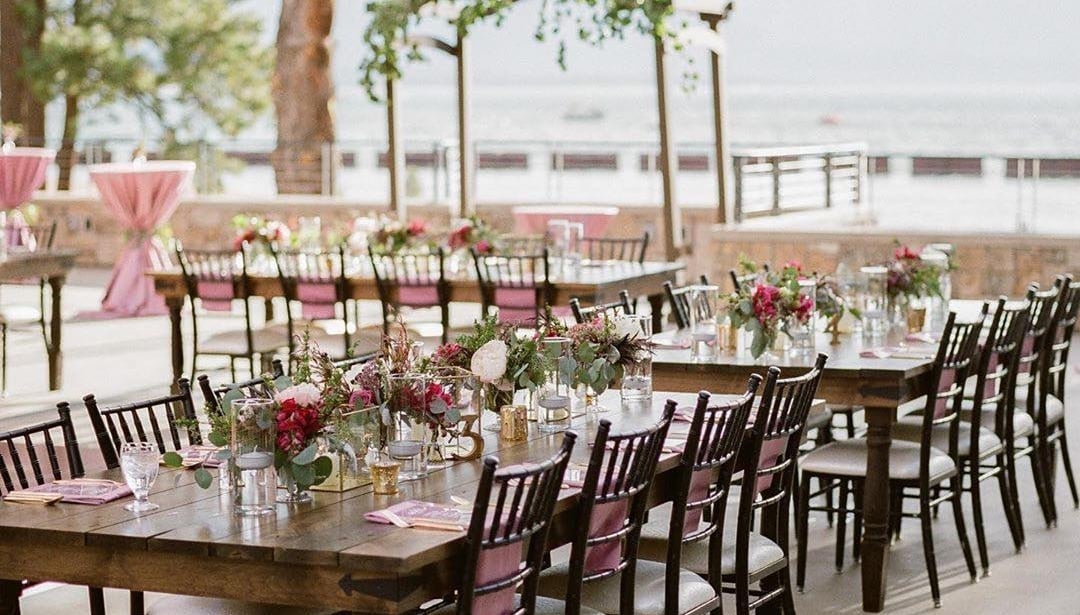 a beautifully set outdoor dining area with tables, chairs, flowers, and candles