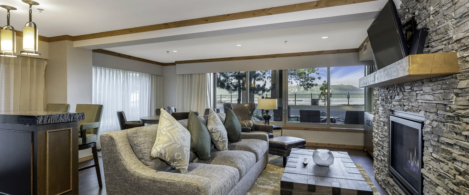 Sofa and armchair overlooking the TV placed on the accent stone wall above the fireplace