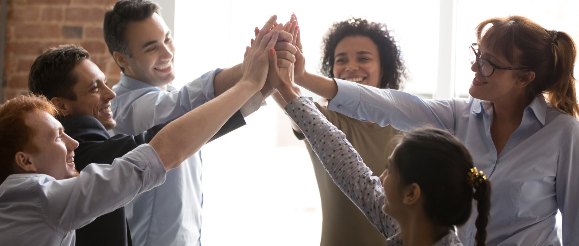 A group of people raising their arms to join palms of their hands