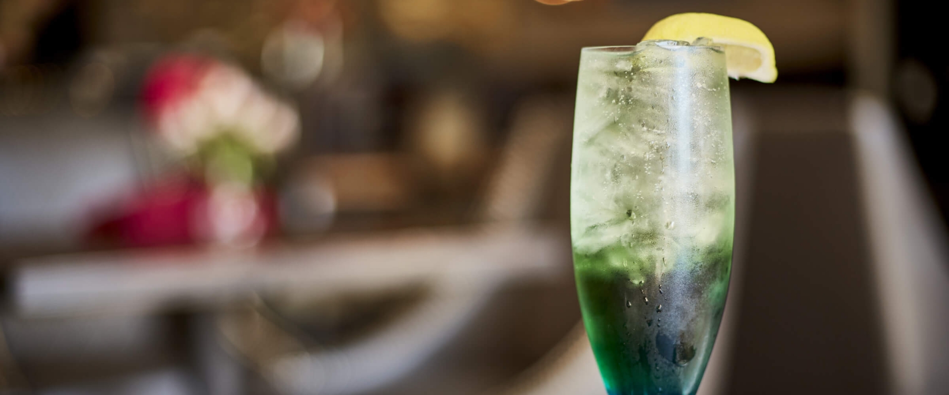 A green cocktail with a lemon wedge placed on the rim of the glass