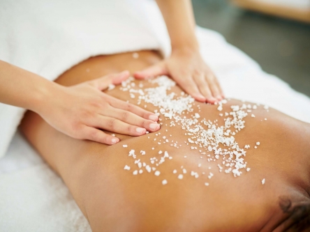 A woman receiving an exfoliating massage from the hands of the therapist