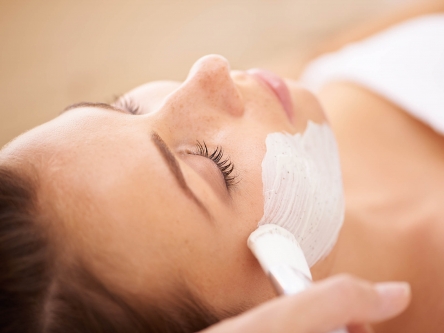 A close up of a beauty therapist applying a face mask to a woman's cheeks