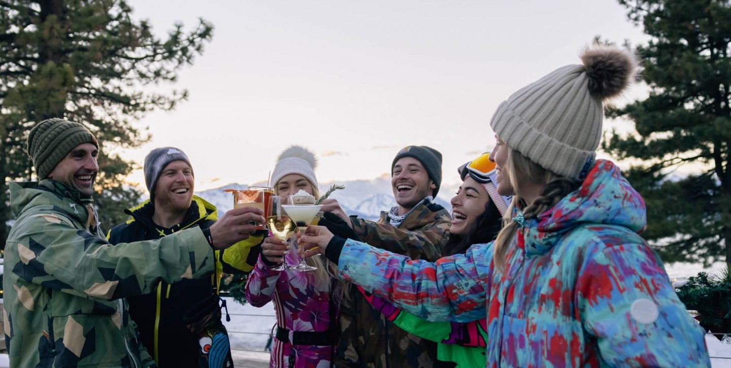 Friends clinking their drinks together outside in their ski clothes