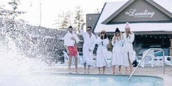 Group of friends laughing by the pool in robes