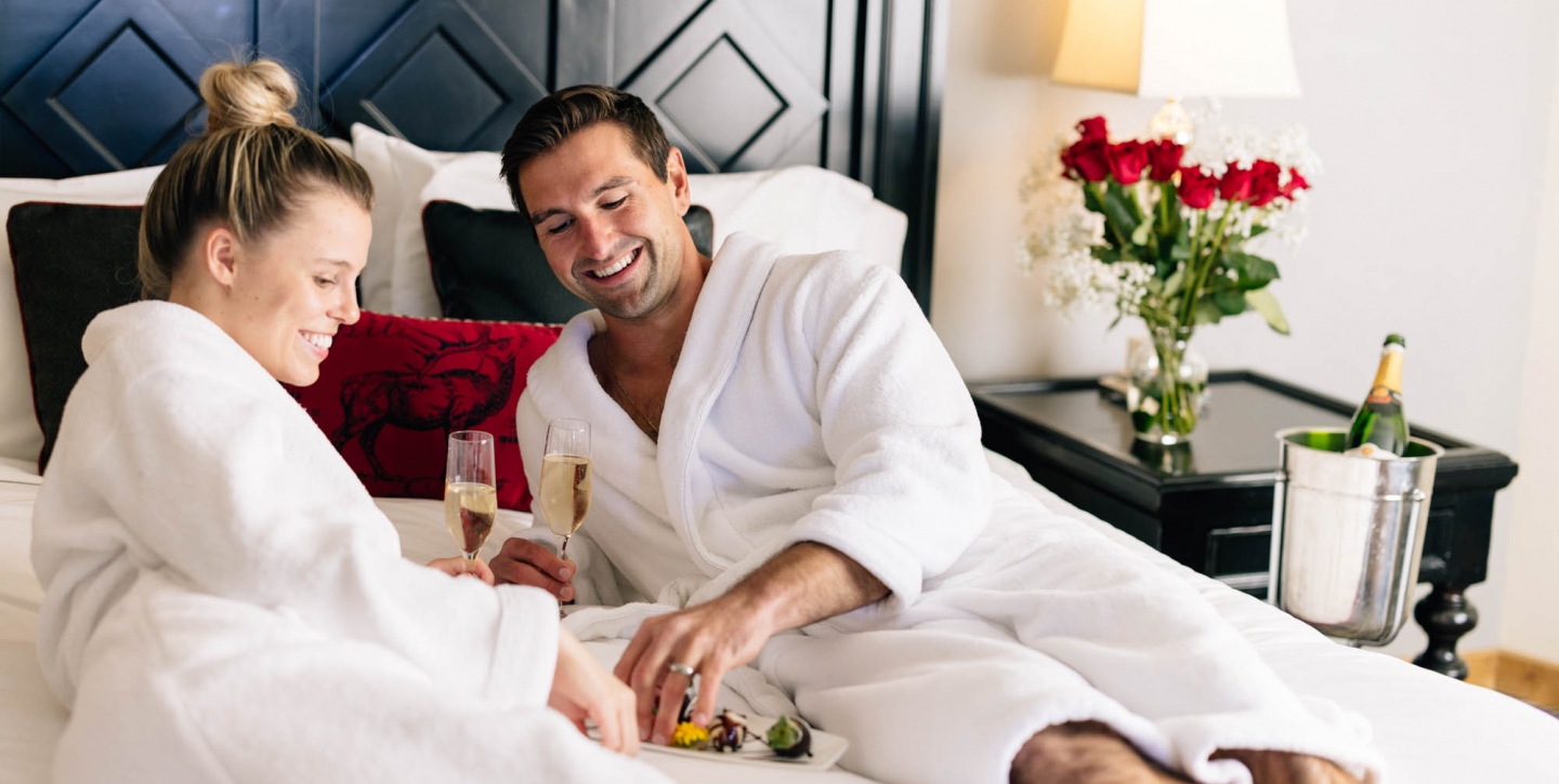 Couple enjoying breakfast in bed with champagne