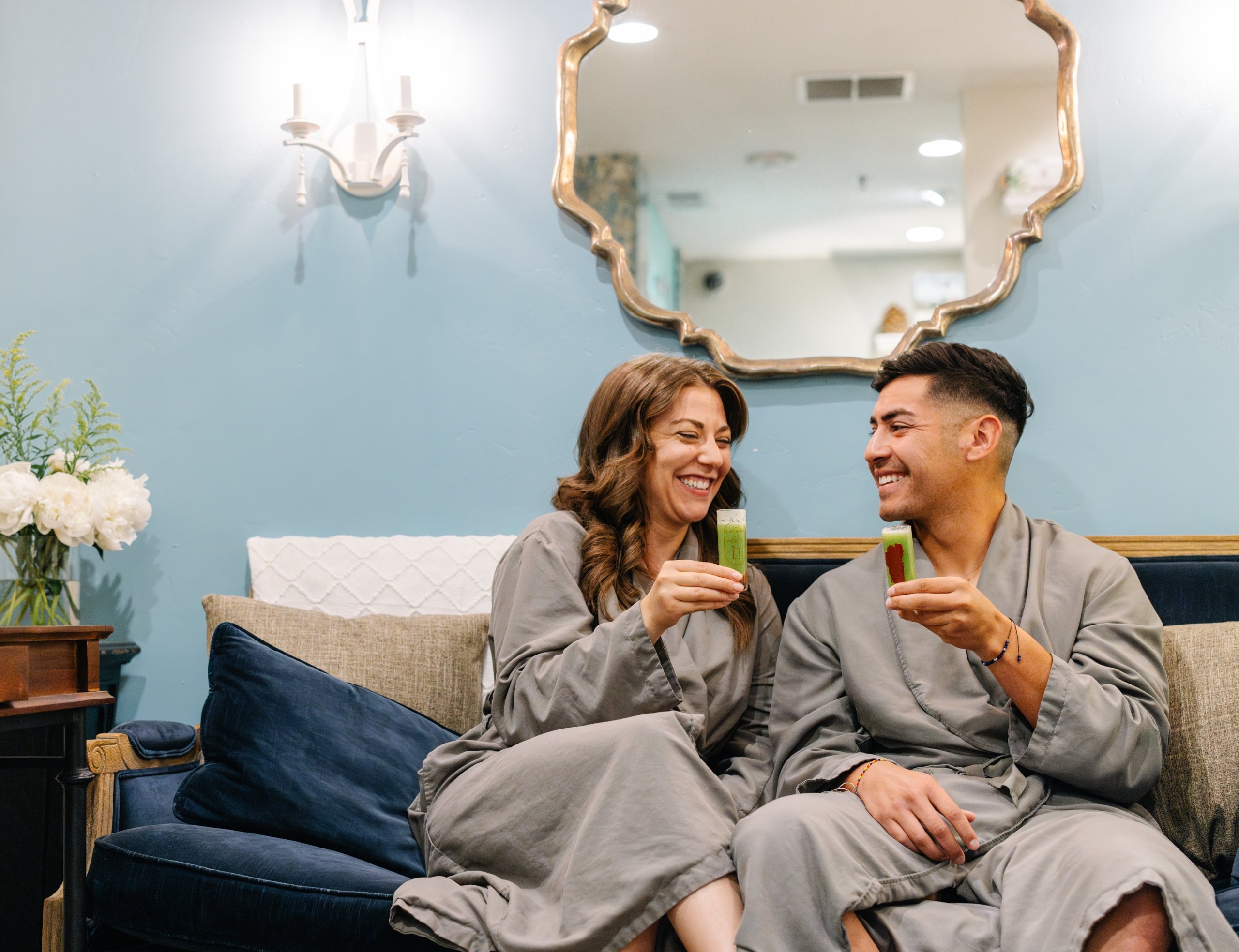 A couple in spa robes taking wellness shots