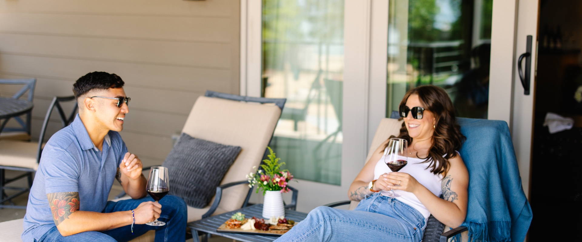 A couple lounging on patio chairs with glasses of wine