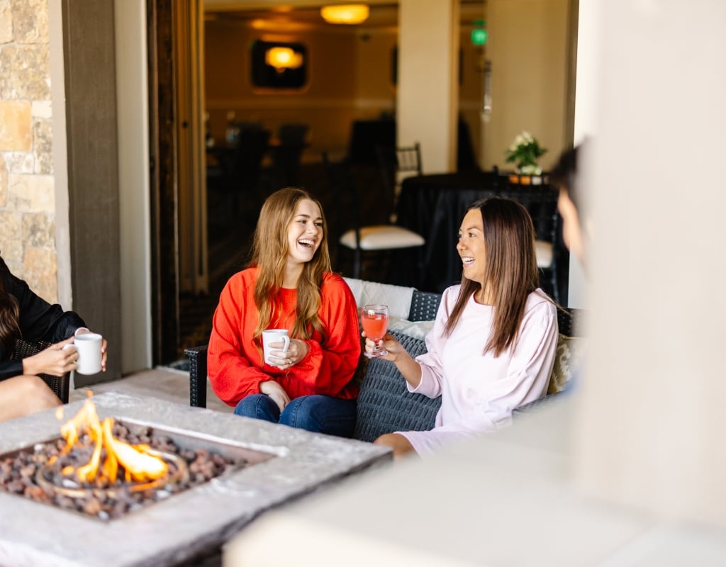 A group of people sitting around a fire pit in an outdoor seating area.