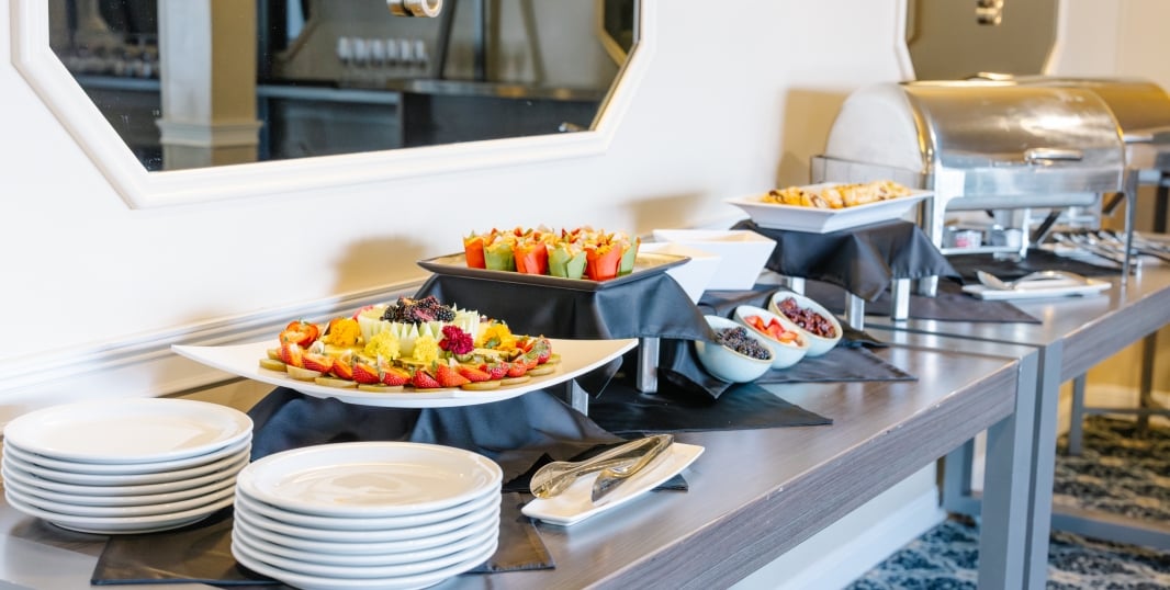 A buffet table with various dishes and plates of food.