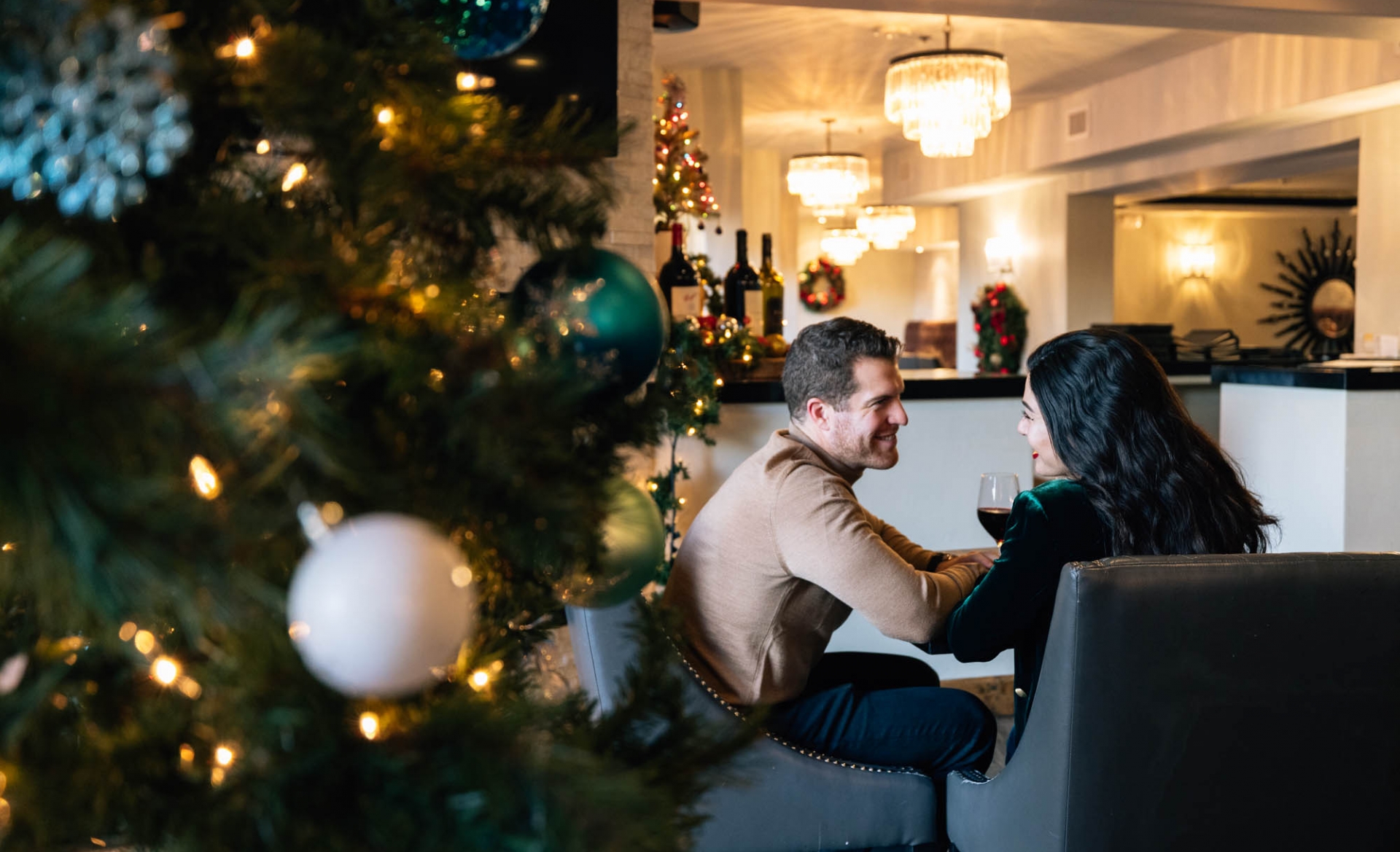 A couple enjoying a drink next to a Christmas tree