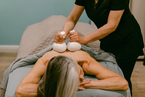 a woman receiving a massage with hot stones on her back