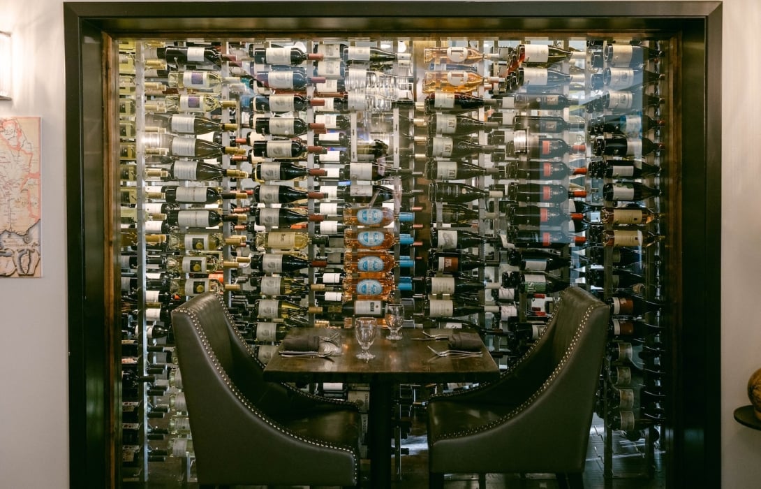 Table with two seats with wine bottles in the back