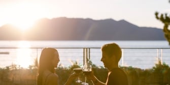 Two people clinking wine glasses outside