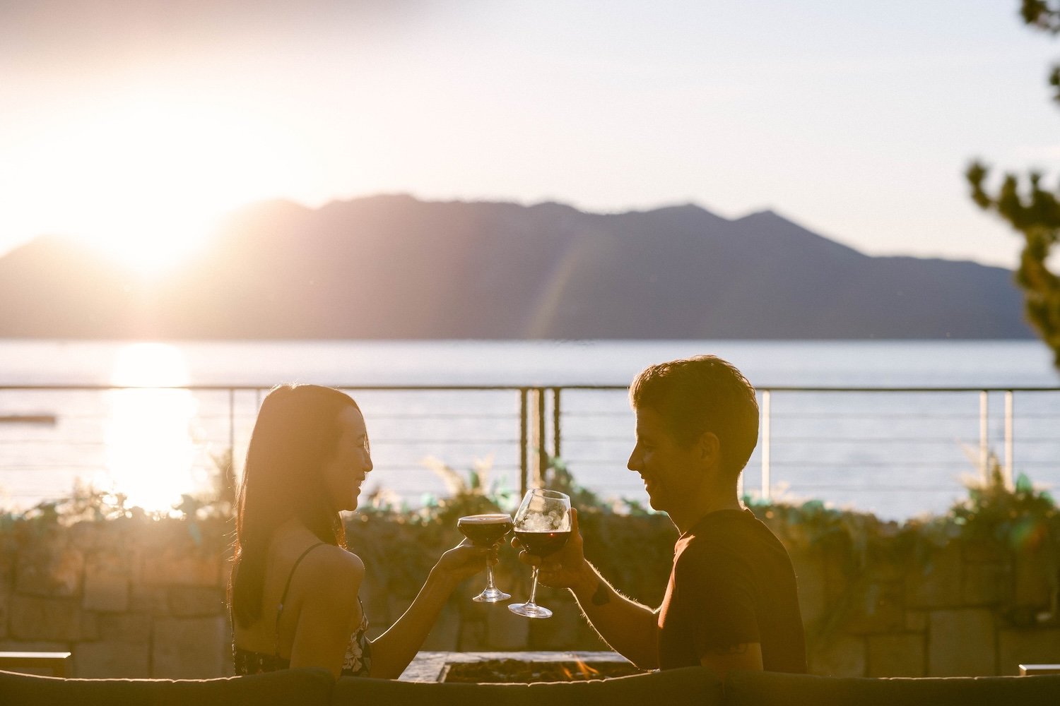 Two people clinking wine glasses outside