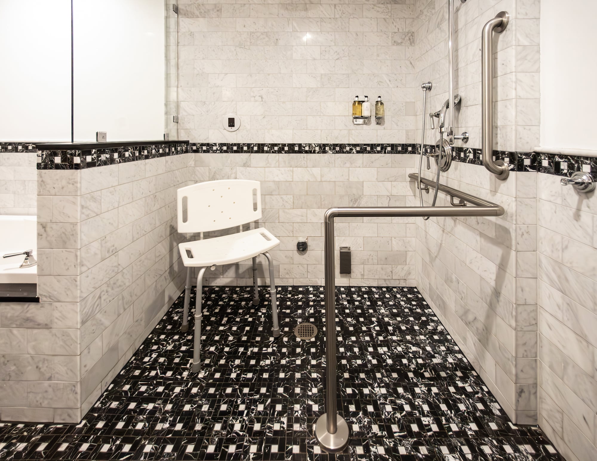 A bathroom with a shower, grab bars, and a shower chair.