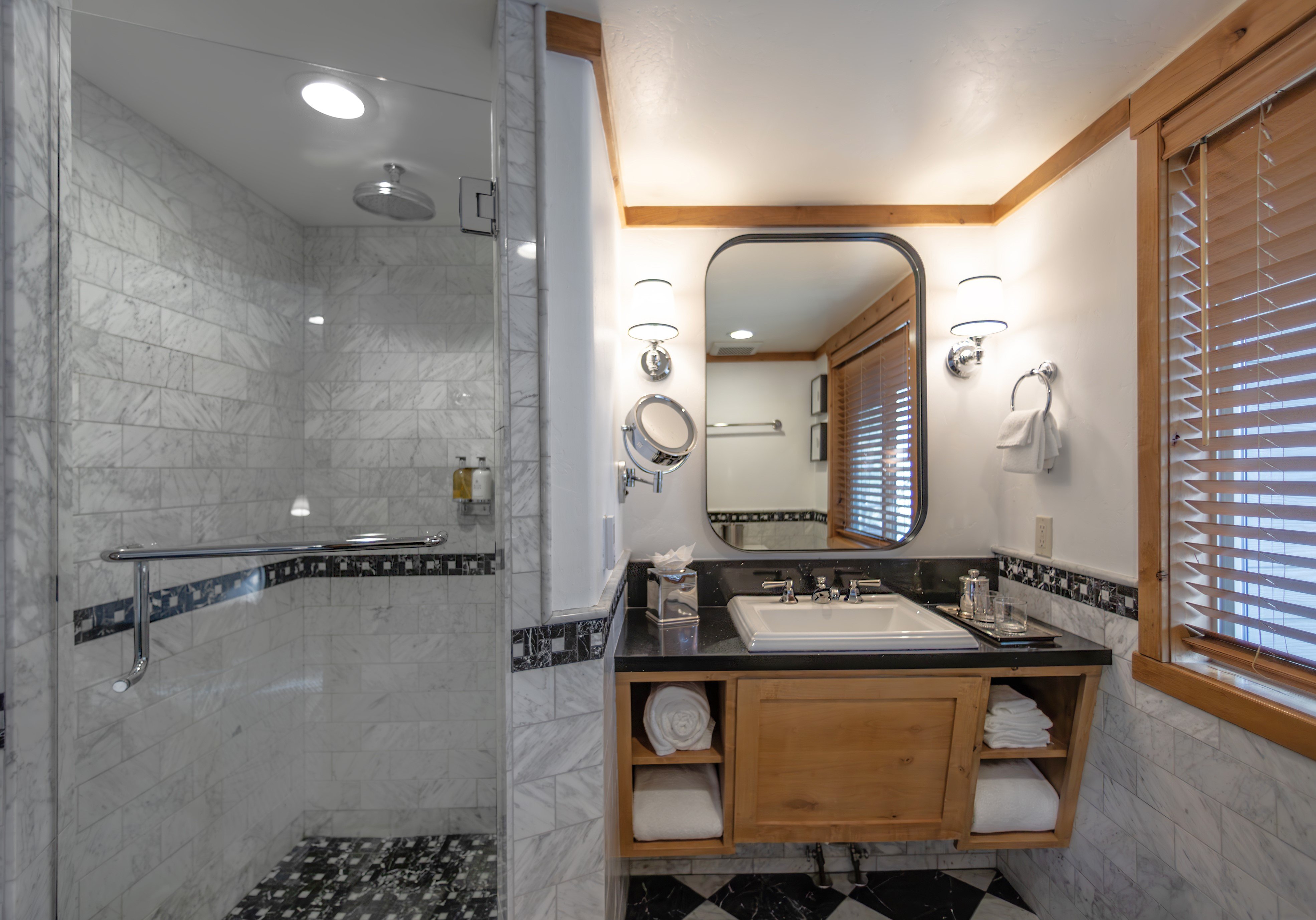 A clean and modern bathroom with a large walk-in shower, double vanity, and large mirror.