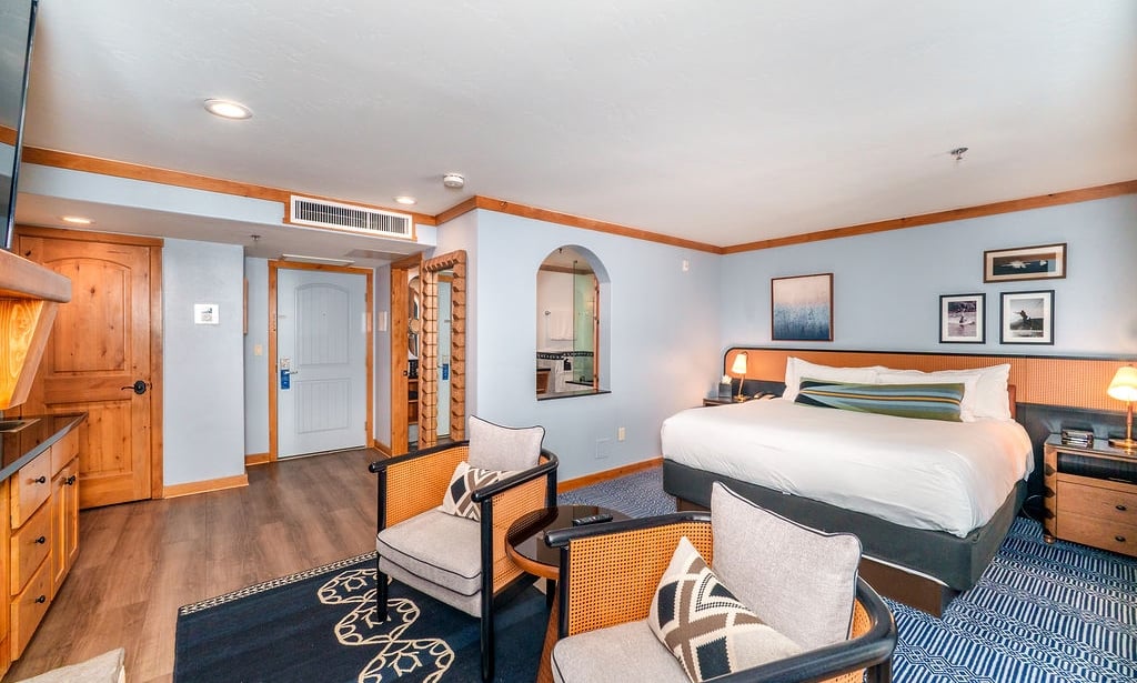 A hotel room with a bed, seating area, and bathroom in the background.